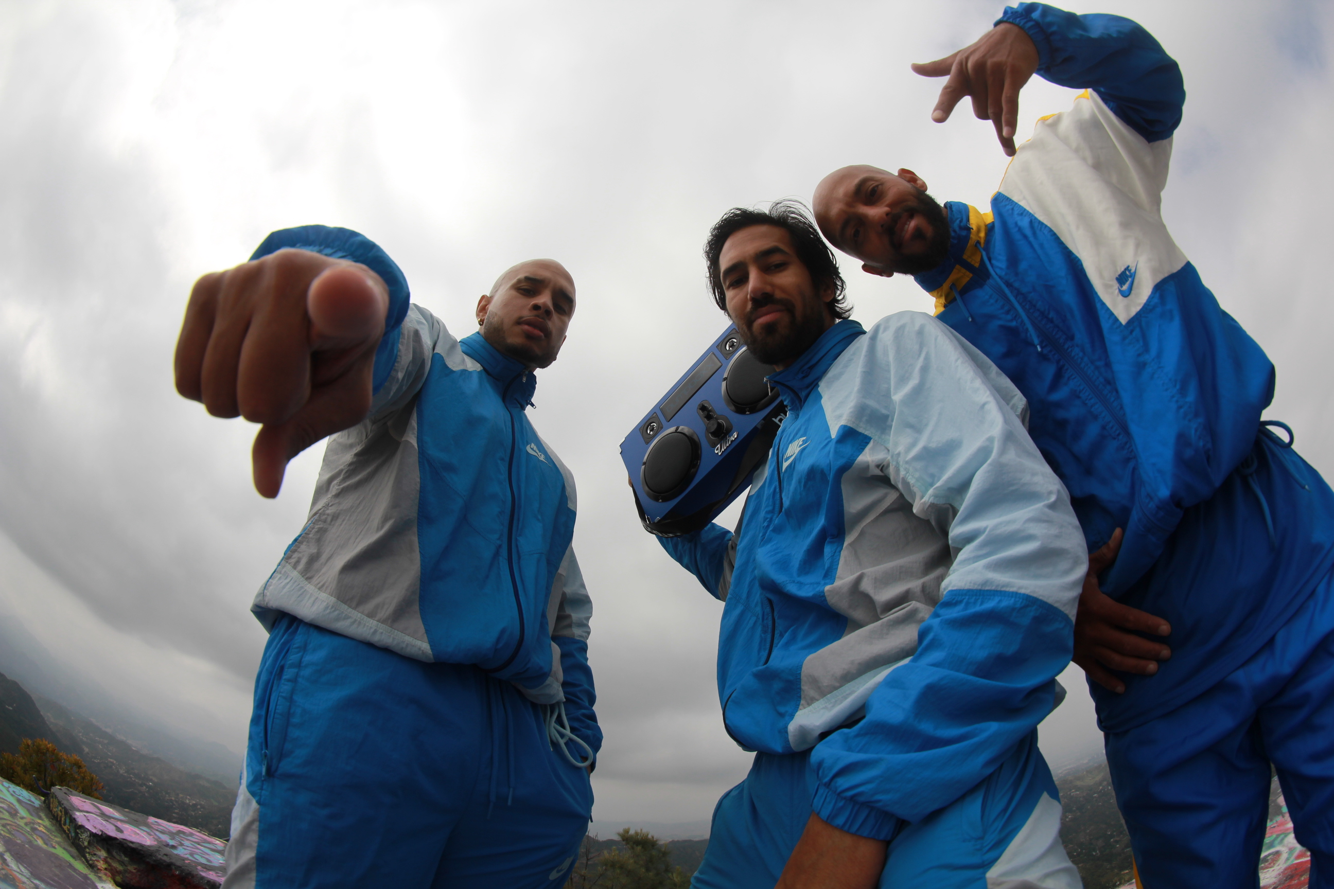The three THEULTRABOYS crew members in blue tracksuits looking into the camera